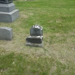 A grave with a prominent tombstone and headstone, nestled in a peaceful burial ground